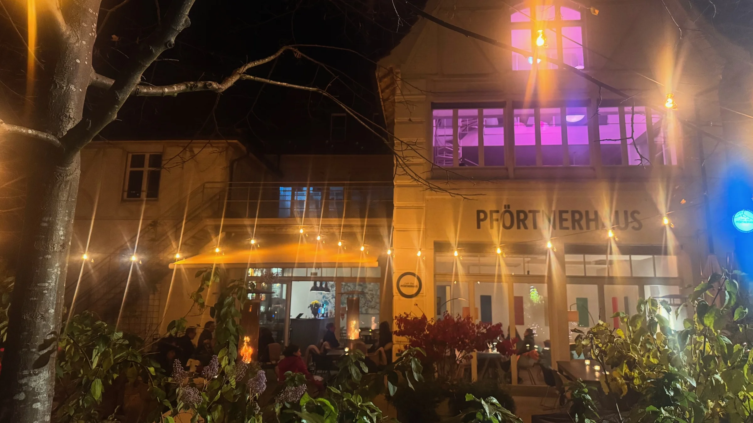 Pförtnerhaus bei Nacht mit beleuchtetem Eventraum und Gartenterrasse